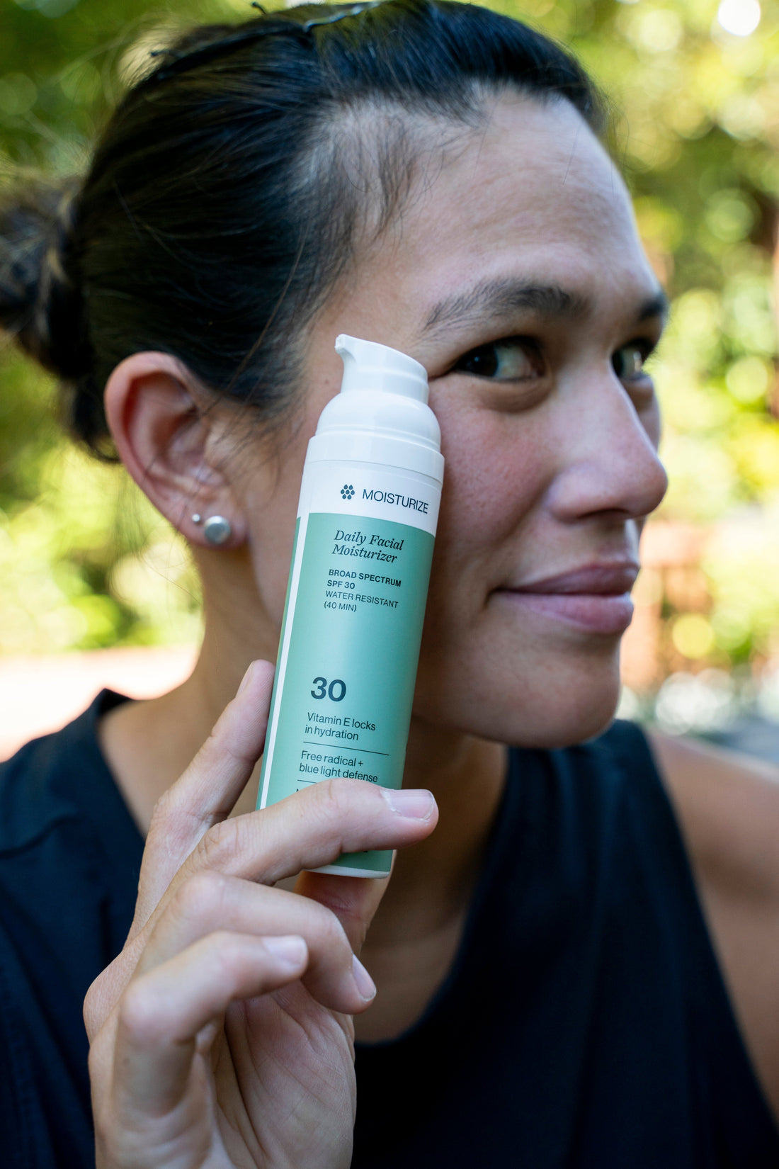 Athlete holding a bottle of sweat-resistant sunscreen to face