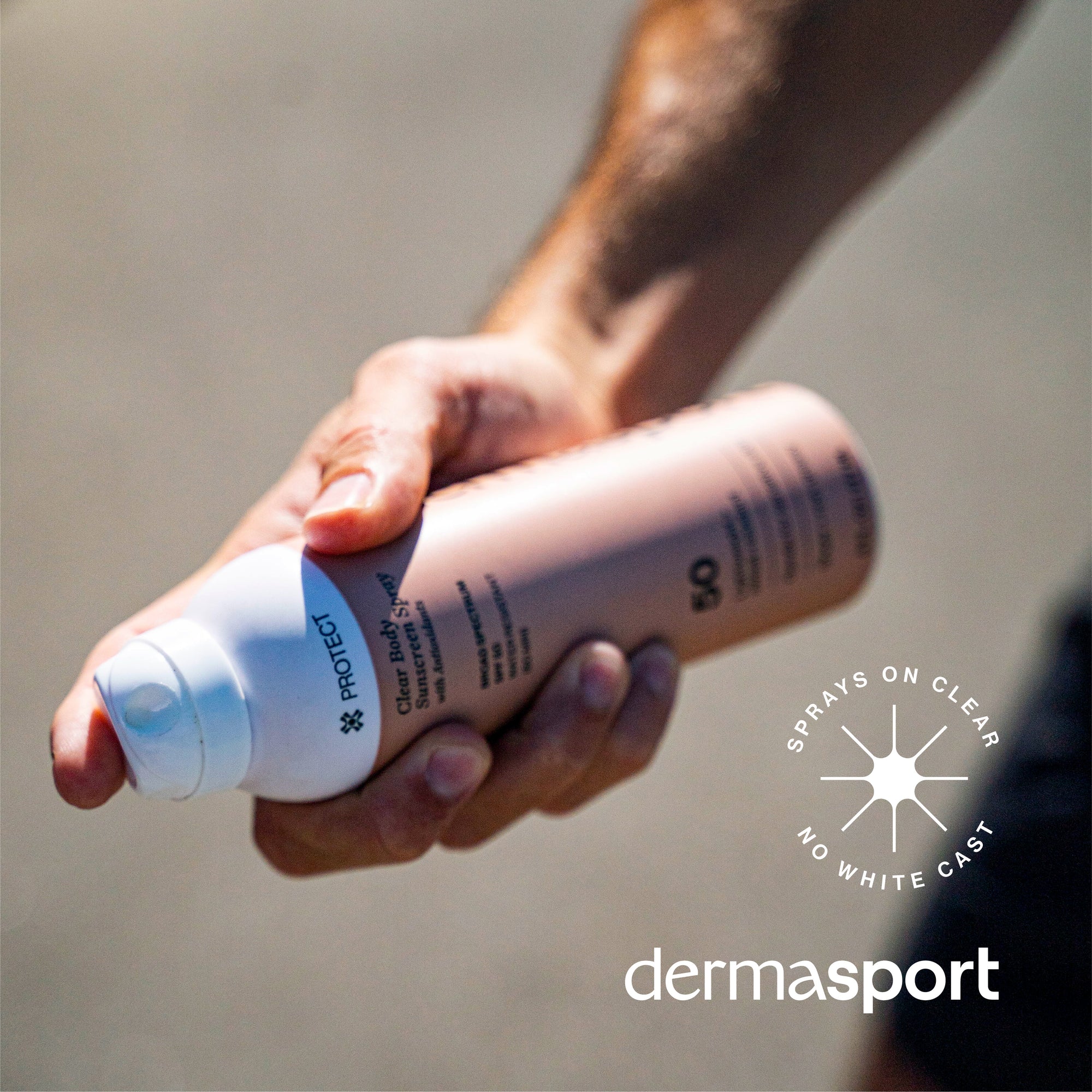 Hand holding a Dermasport spray bottle with a clear background