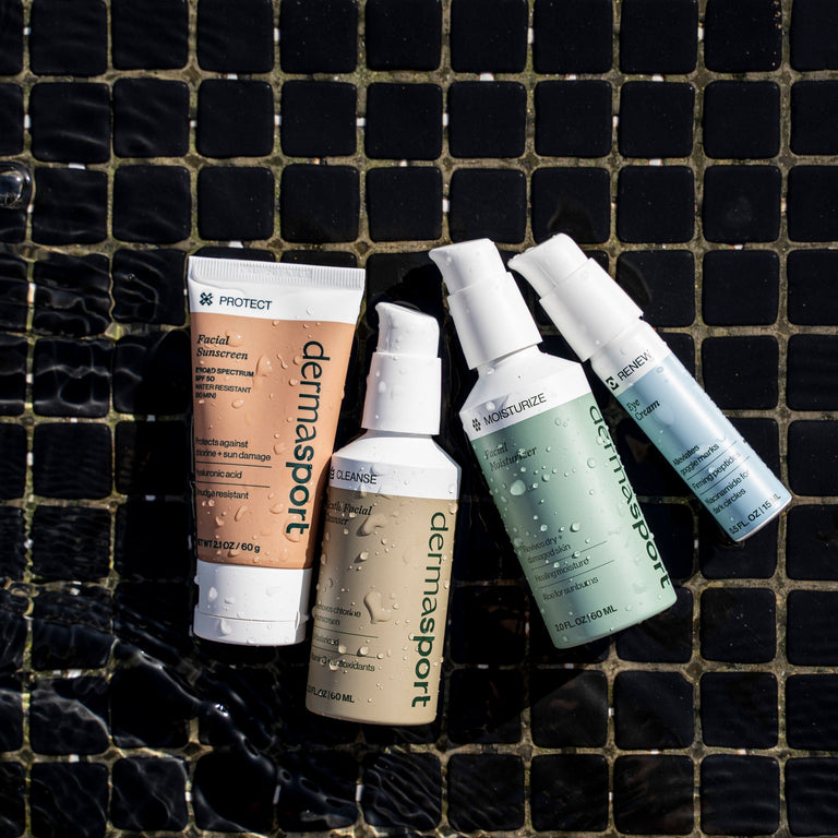 Collection of dermasport skincare products on a black tiled surface