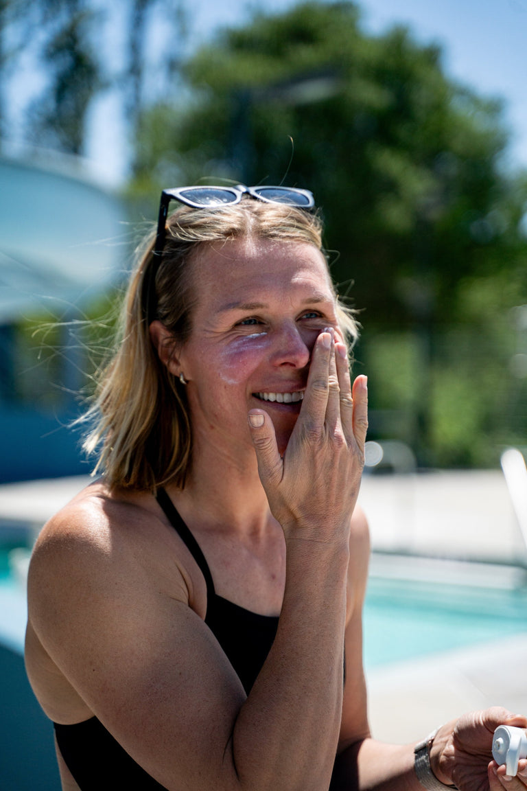 Swimmer applying water resistant mineral sunscreen lotion that is reef-safe.